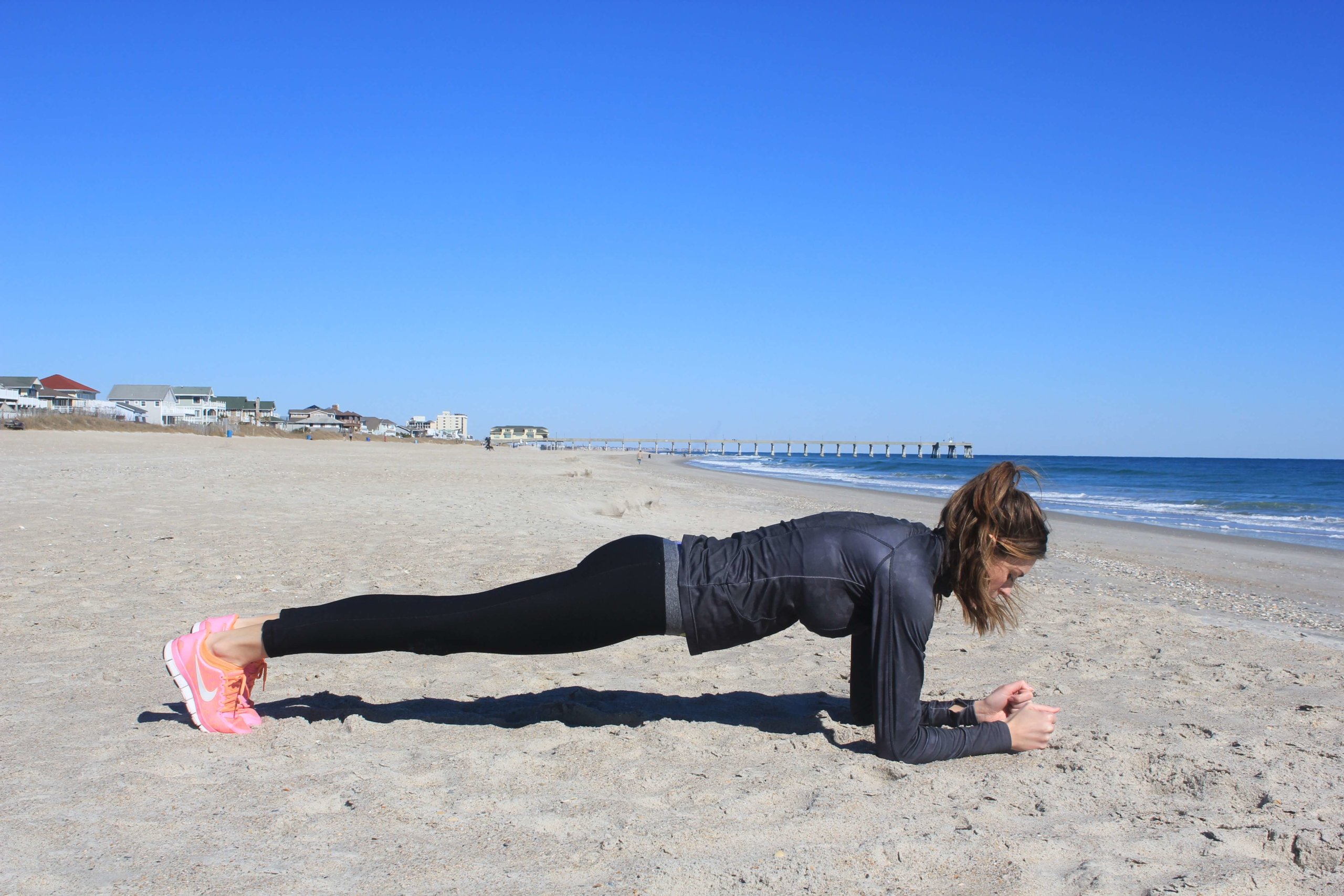 girl in a plank position in sand on the beach
