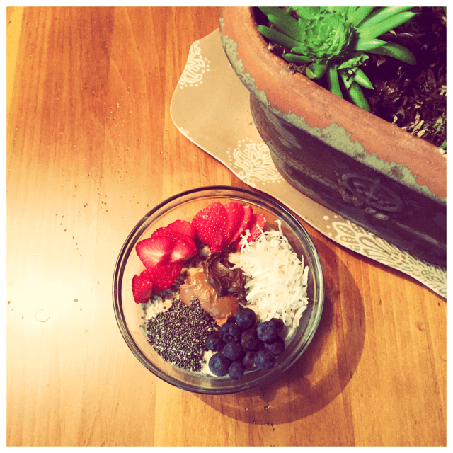 Overnight oats topped with strawberries, blueberries, coconut, chai seeds, peanut butter, and cocoa almond spread